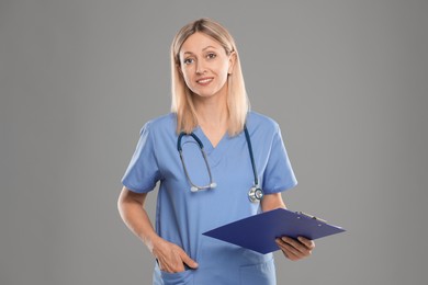 Photo of Portrait of nurse in medical uniform with stethoscope and clipboard on grey background