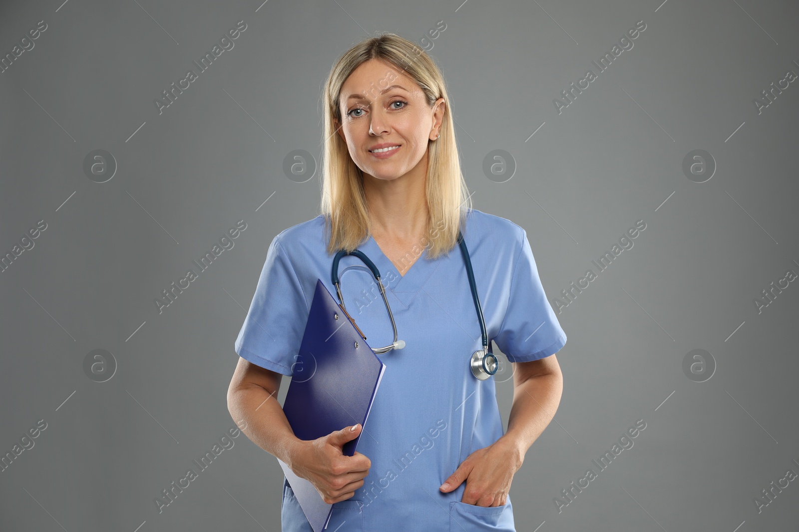 Photo of Portrait of nurse in medical uniform with stethoscope and clipboard on grey background