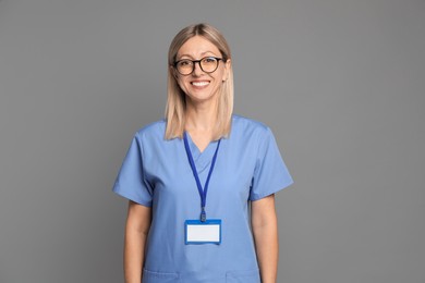 Photo of Nurse in medical uniform with badge on grey background