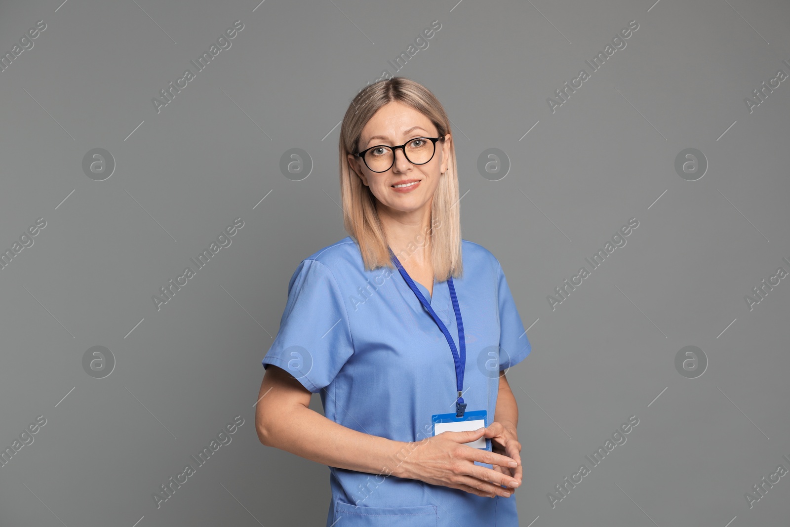 Photo of Nurse in medical uniform with badge on grey background