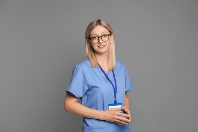 Nurse in medical uniform with badge on grey background