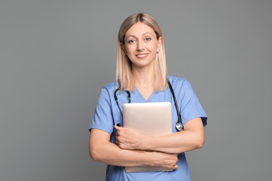 Photo of Doctor in medical uniform with stethoscope and laptop on grey background