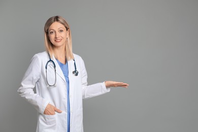 Portrait of doctor in medical uniform with stethoscope on grey background, space for text