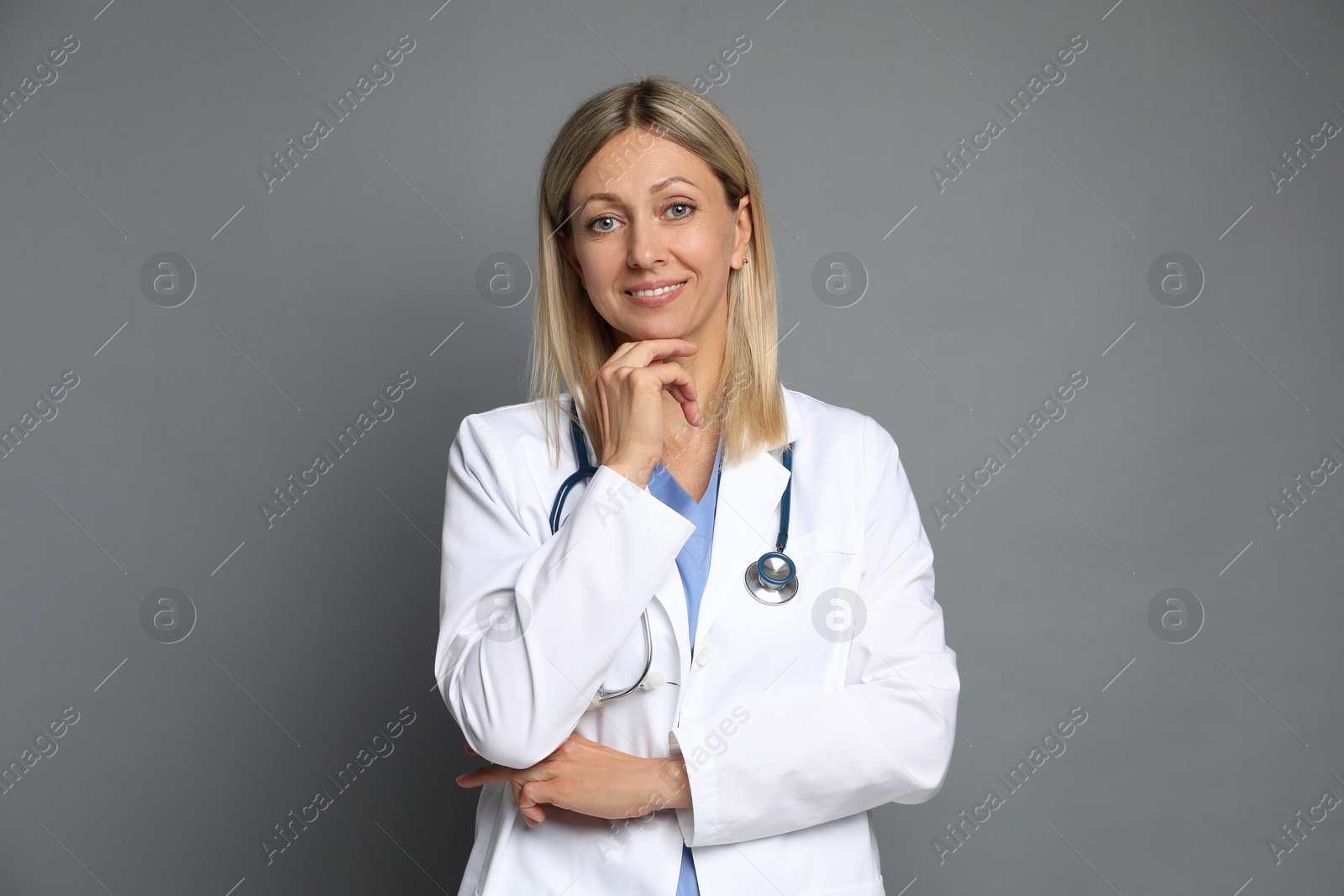 Photo of Portrait of doctor in medical uniform with stethoscope on grey background