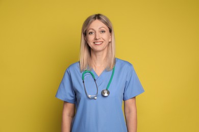 Portrait of nurse in medical uniform with stethoscope on yellow background