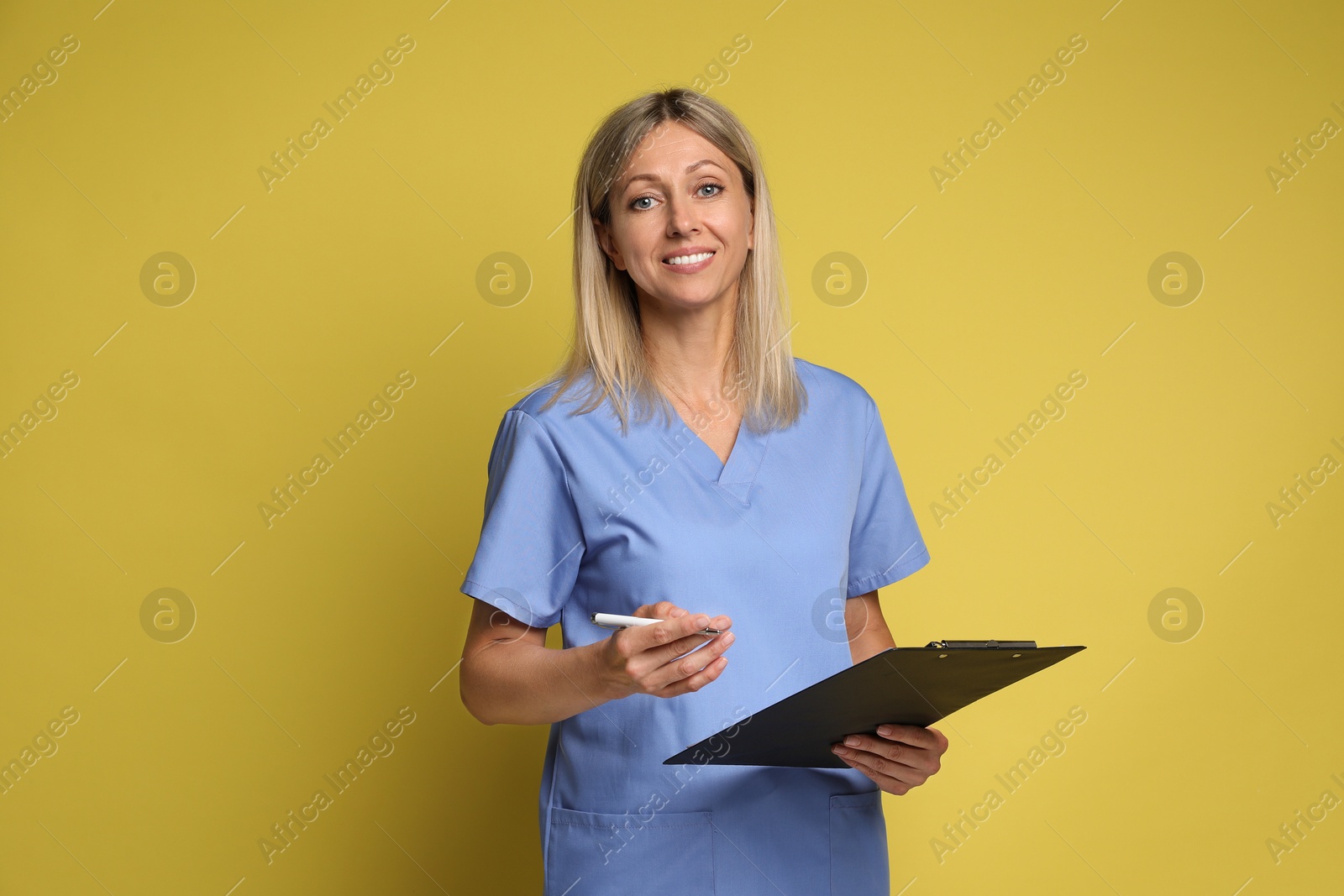 Photo of Portrait of nurse in medical uniform with clipboard on yellow background