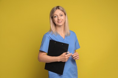 Photo of Portrait of nurse in medical uniform with clipboard on yellow background