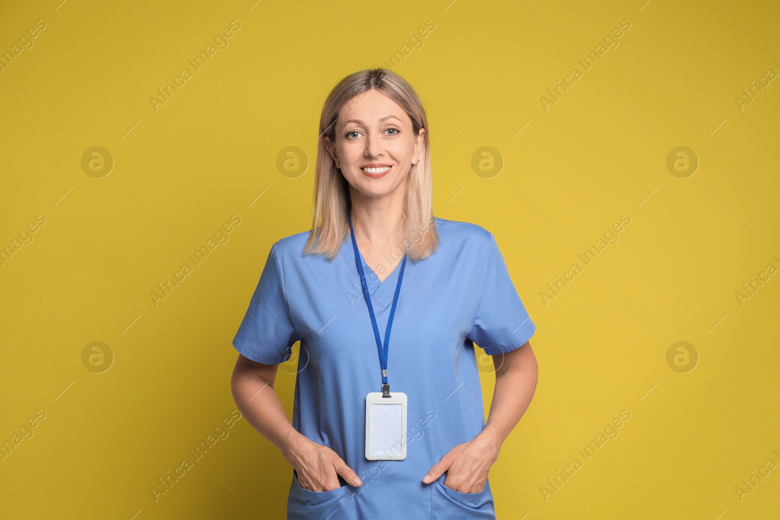 Photo of Portrait of nurse in medical uniform with badge on yellow background