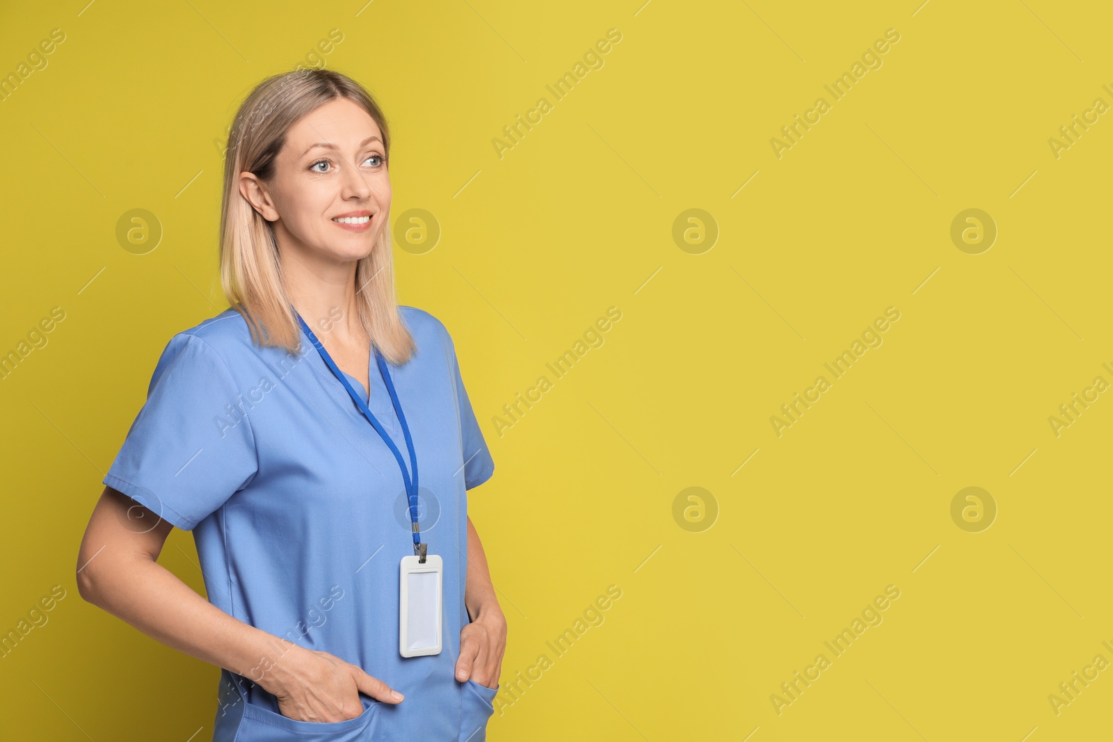 Photo of Nurse in medical uniform with badge on yellow background, space for text