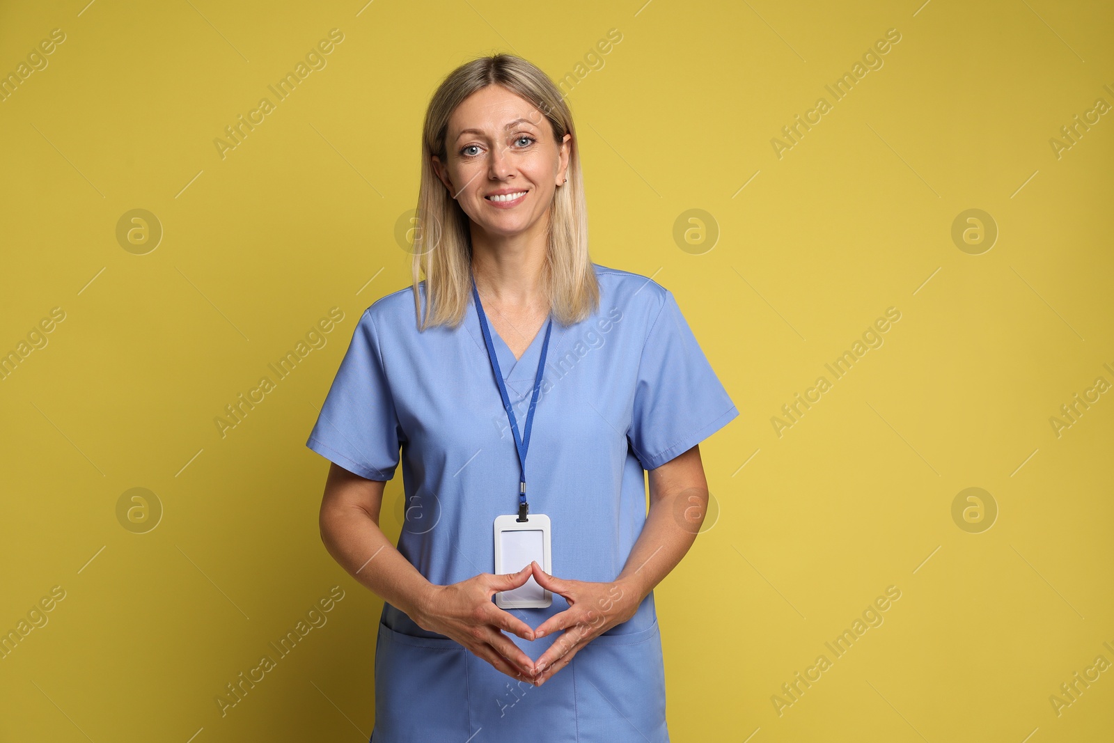 Photo of Portrait of nurse in medical uniform with badge on yellow background