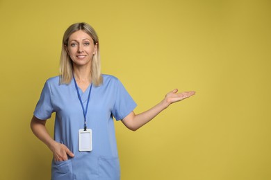 Portrait of nurse in medical uniform with badge on yellow background, space for text