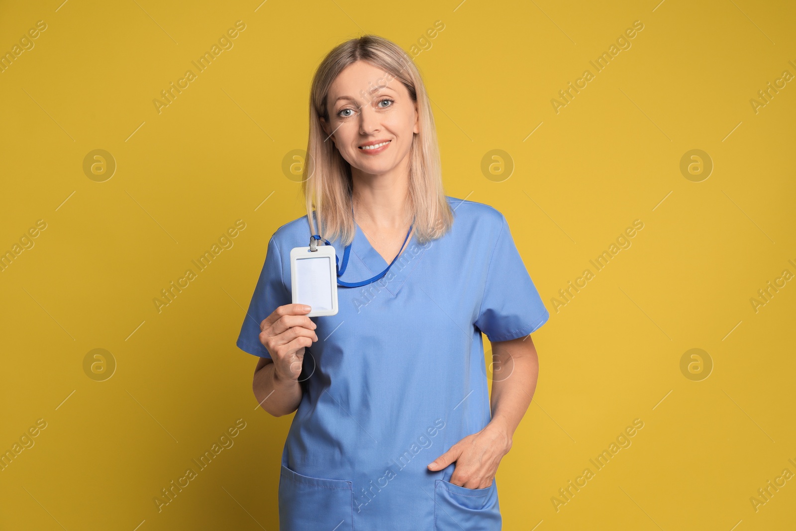 Photo of Portrait of nurse in medical uniform with badge on yellow background