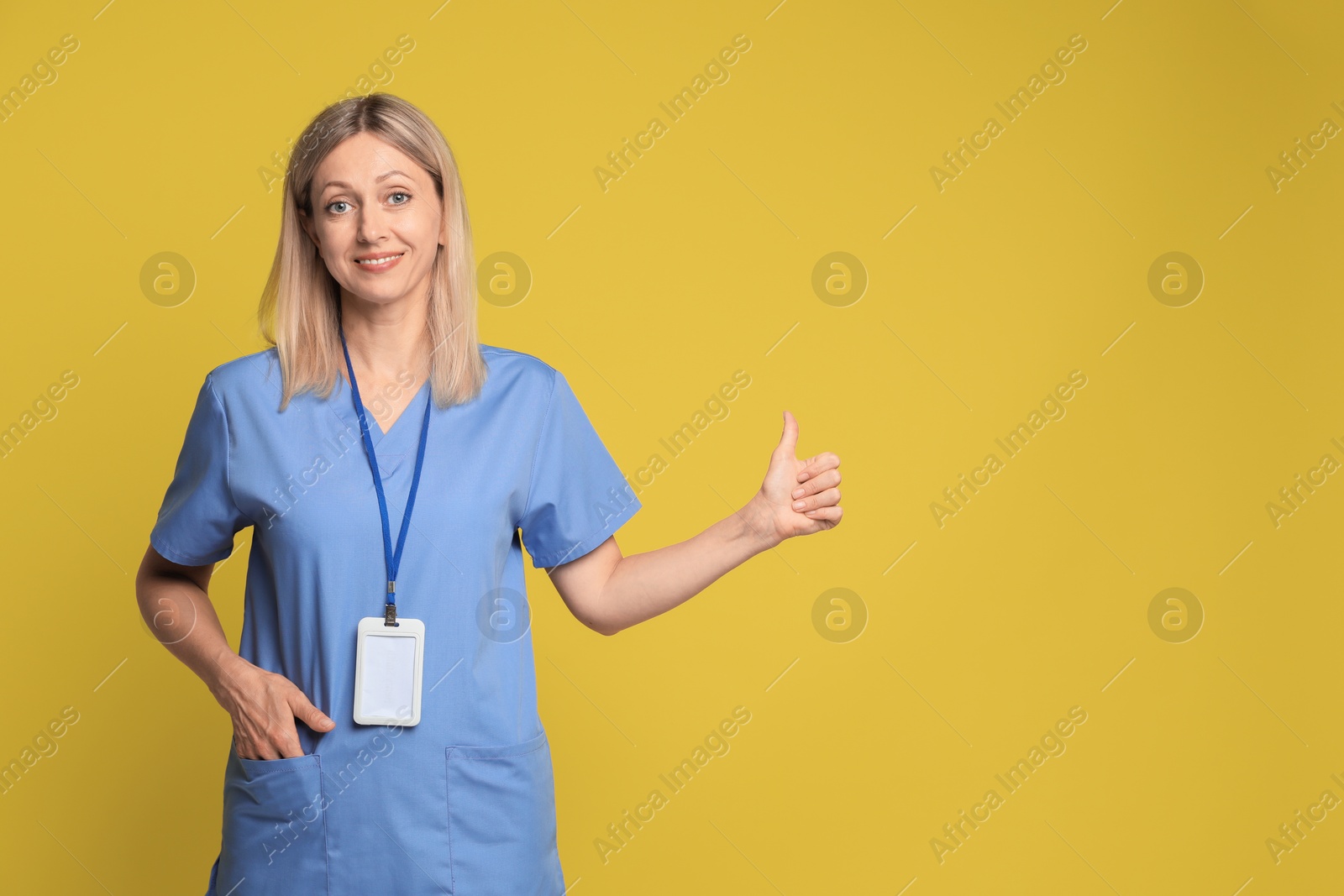 Photo of Portrait of nurse in medical uniform with badge on yellow background, space for text