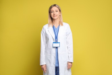 Photo of Portrait of doctor in medical uniform with badge on yellow background