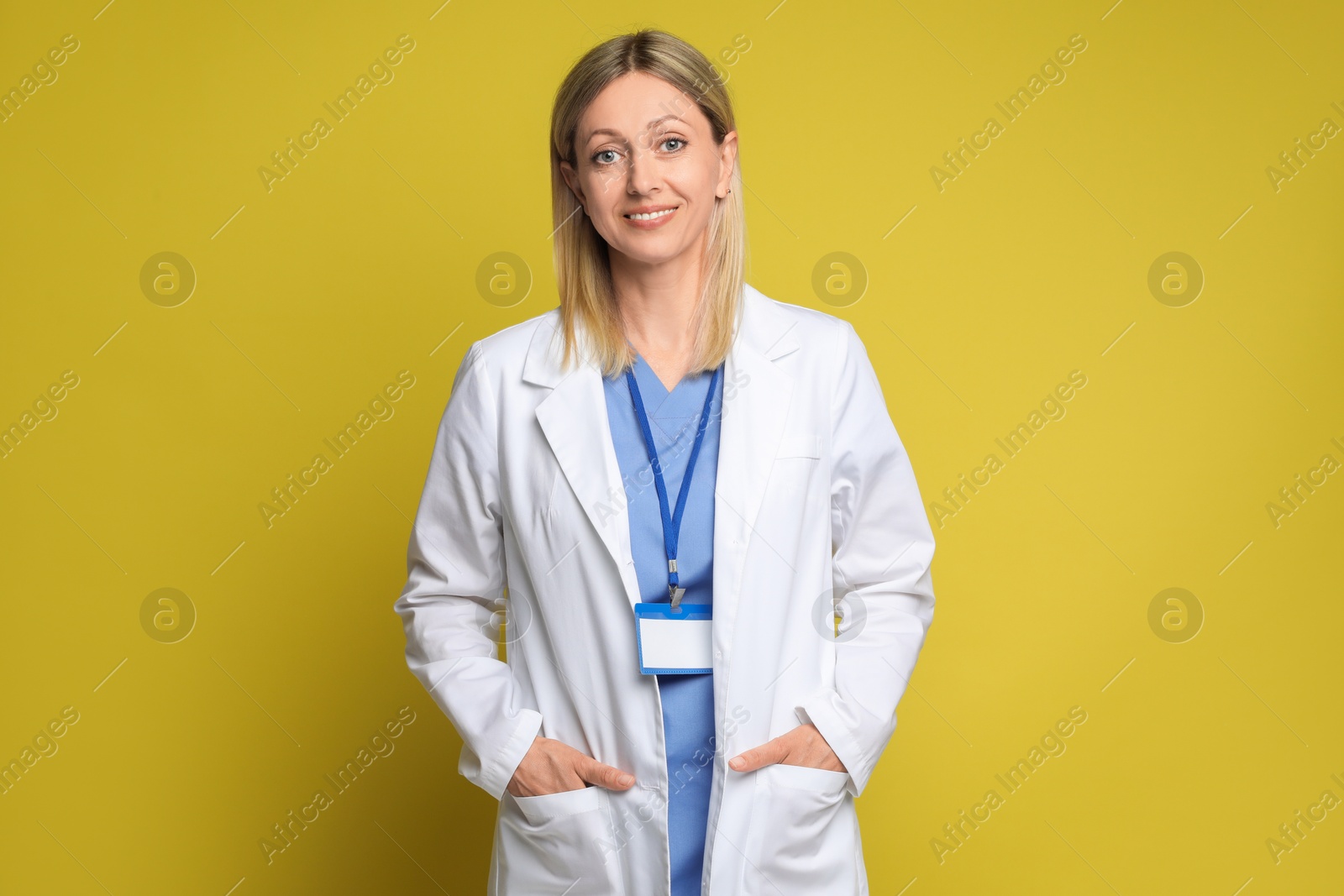 Photo of Portrait of doctor in medical uniform with badge on yellow background