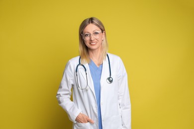 Photo of Portrait of doctor in medical uniform with stethoscope on yellow background