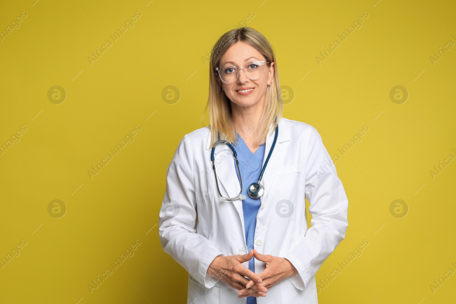 Photo of Portrait of doctor in medical uniform with stethoscope on yellow background