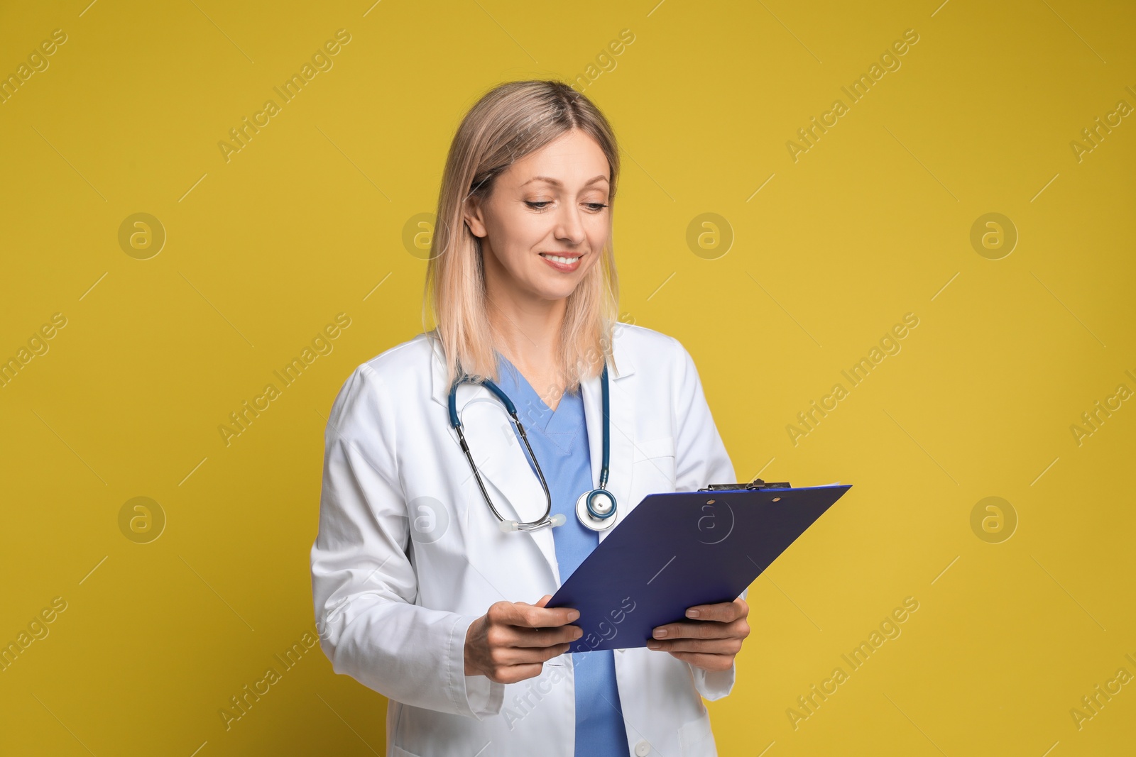 Photo of Doctor in medical uniform with stethoscope and clipboard on yellow background