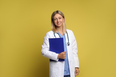 Photo of Portrait of doctor in medical uniform with stethoscope and clipboard on yellow background