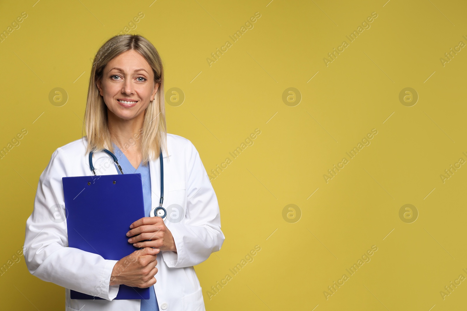 Photo of Portrait of doctor in medical uniform with stethoscope and clipboard on yellow background, space for text