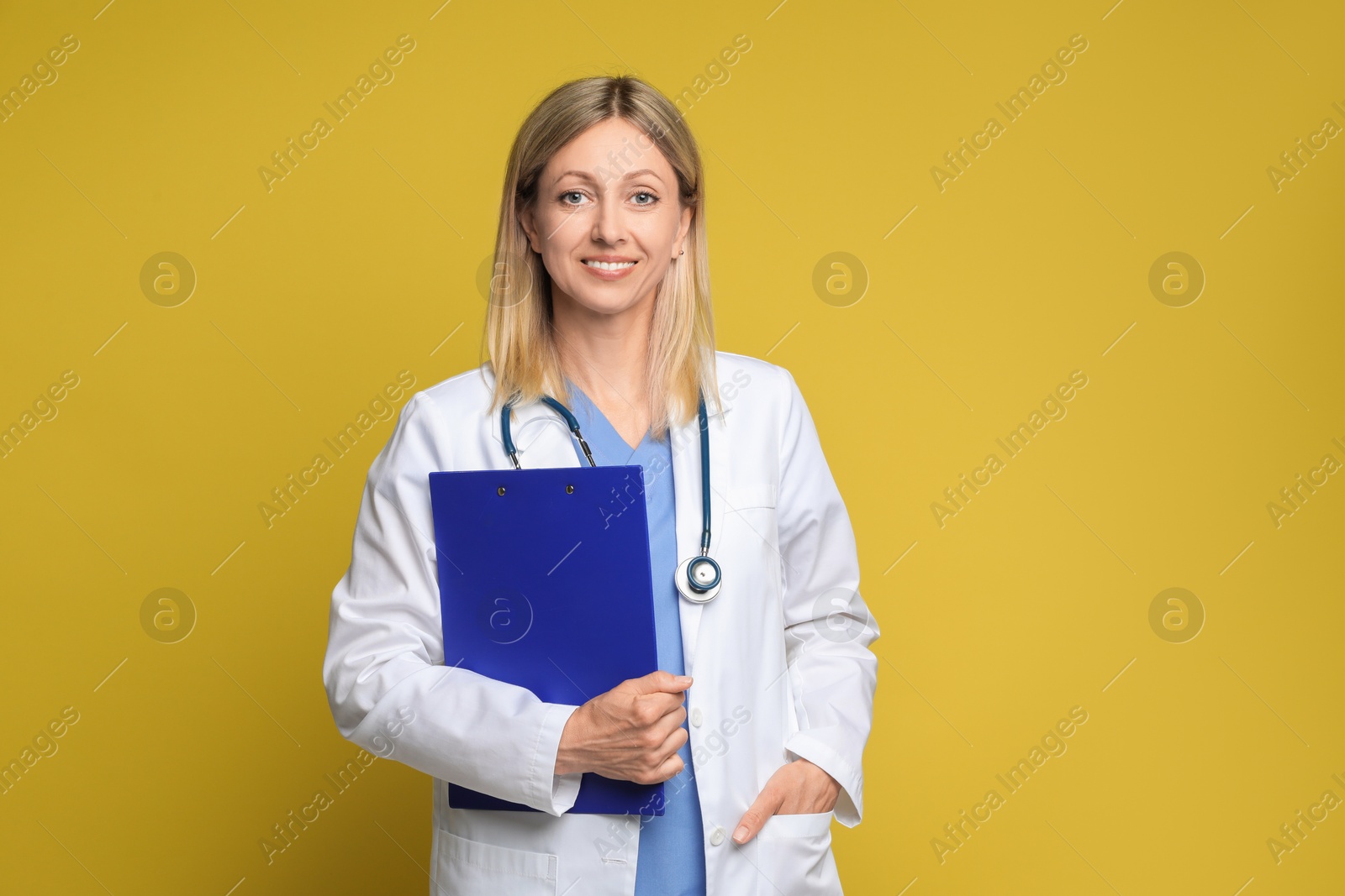 Photo of Portrait of doctor in medical uniform with stethoscope and clipboard on yellow background