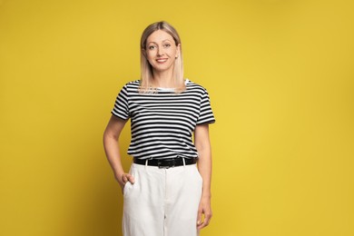 Portrait of beautiful smiling woman on yellow background