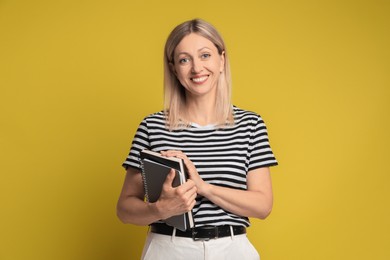 Photo of Beautiful smiling woman with notebooks on yellow background