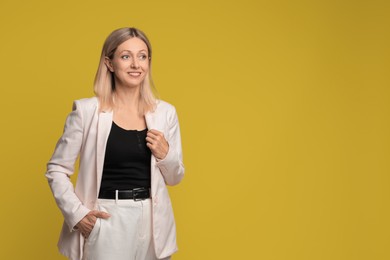 Portrait of beautiful smiling woman on yellow background, space for text