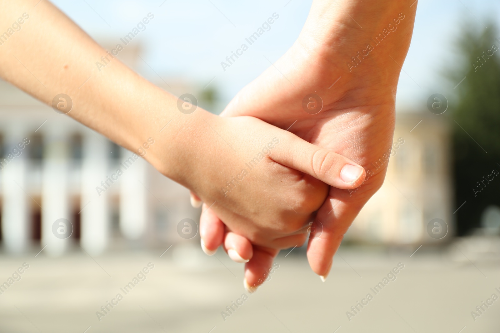 Photo of Mother and daughter holding hands outdoors, closeup