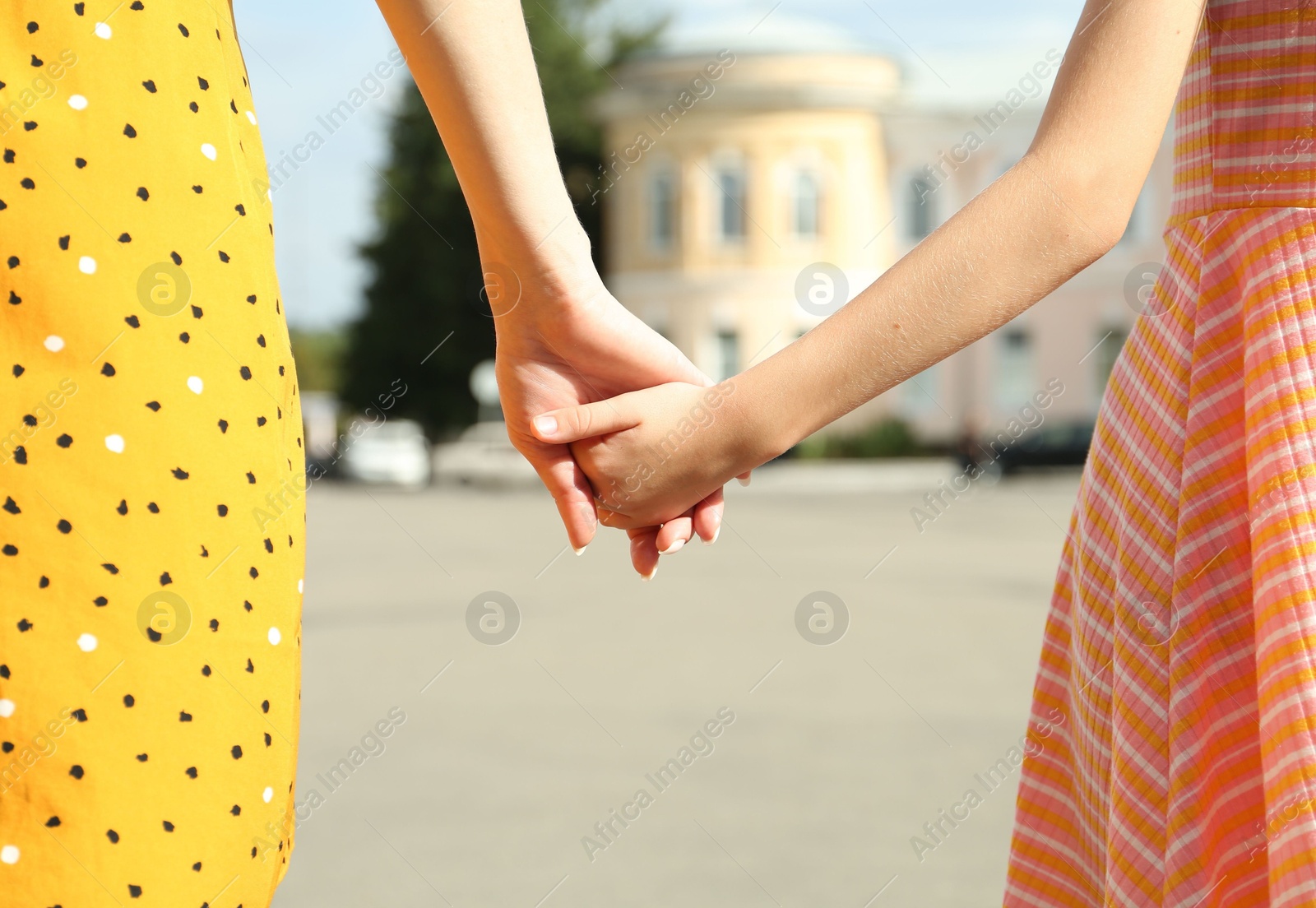 Photo of Mother and daughter holding hands outdoors, closeup