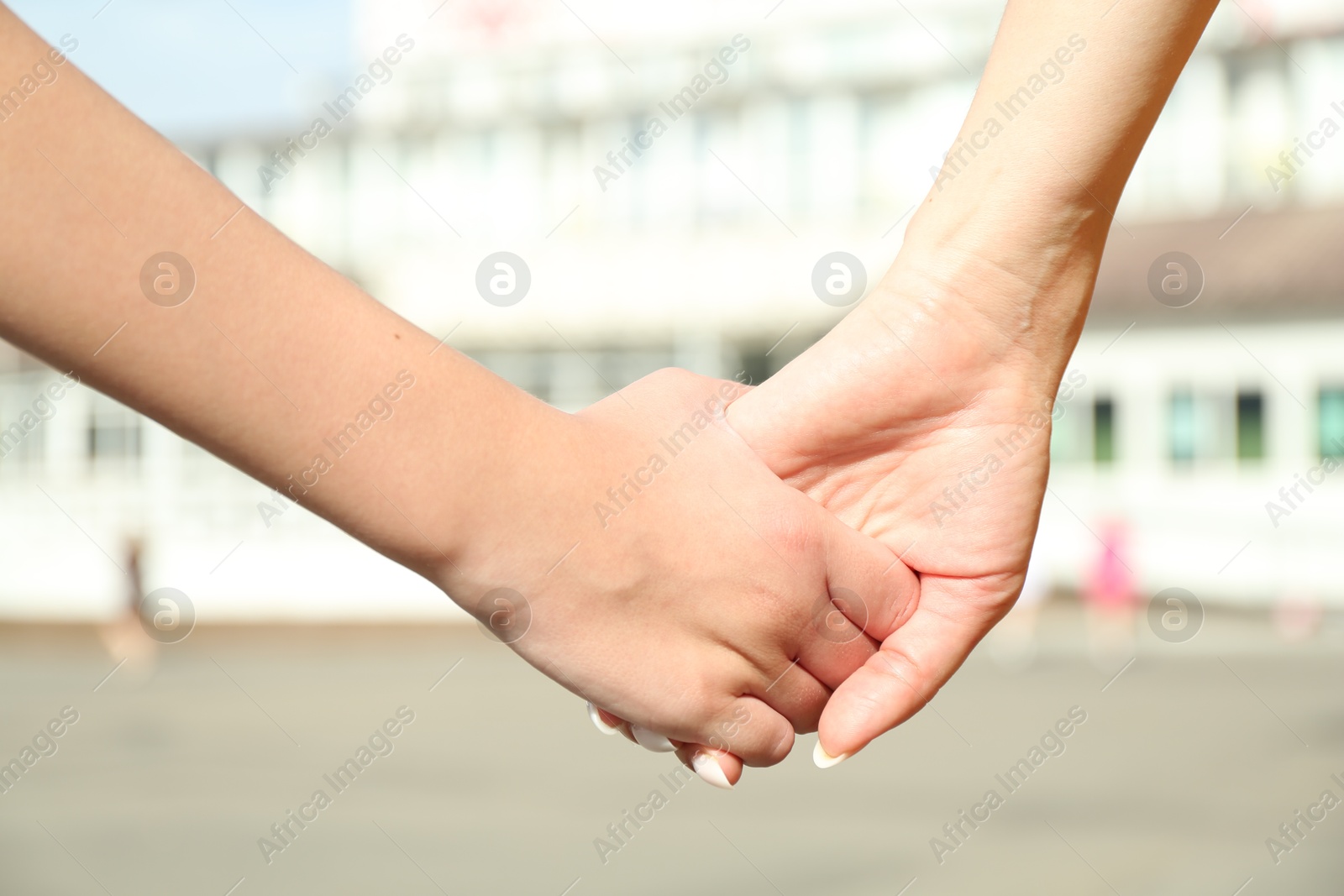 Photo of Mother and daughter holding hands outdoors, closeup