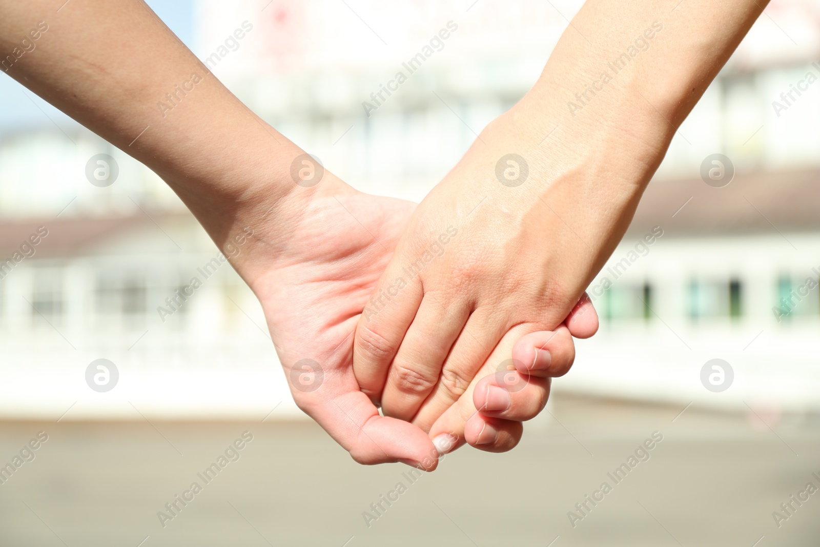 Photo of Mother and daughter holding hands outdoors, closeup