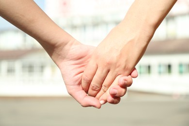 Photo of Mother and daughter holding hands outdoors, closeup