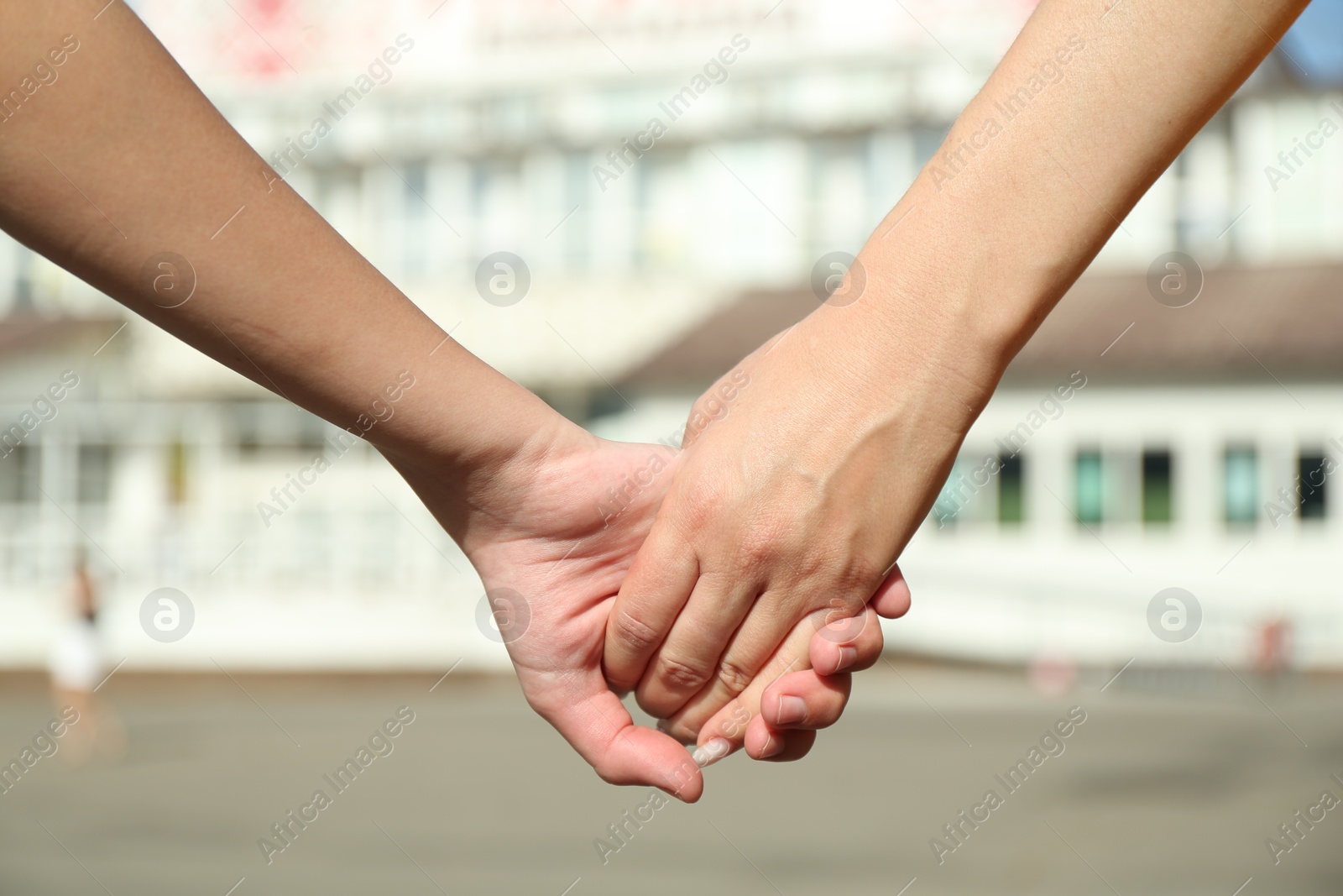 Photo of Mother and daughter holding hands outdoors, closeup