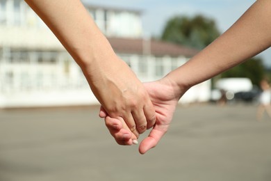 Photo of Mother and daughter holding hands outdoors, closeup