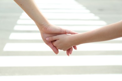 Photo of Mother and daughter holding hands outdoors, closeup