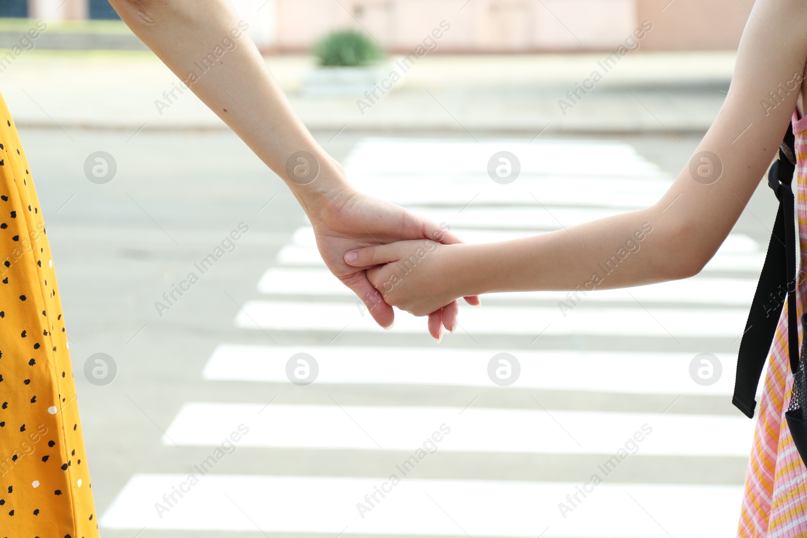 Photo of Mother and daughter holding hands outdoors, closeup