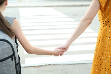 Photo of Mother and daughter holding hands outdoors, closeup