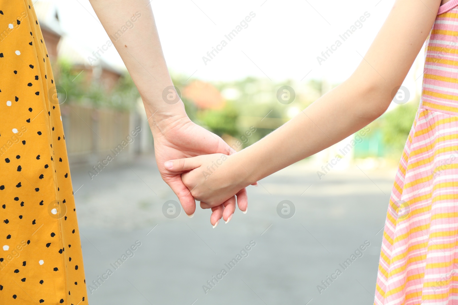 Photo of Mother and daughter holding hands outdoors, closeup