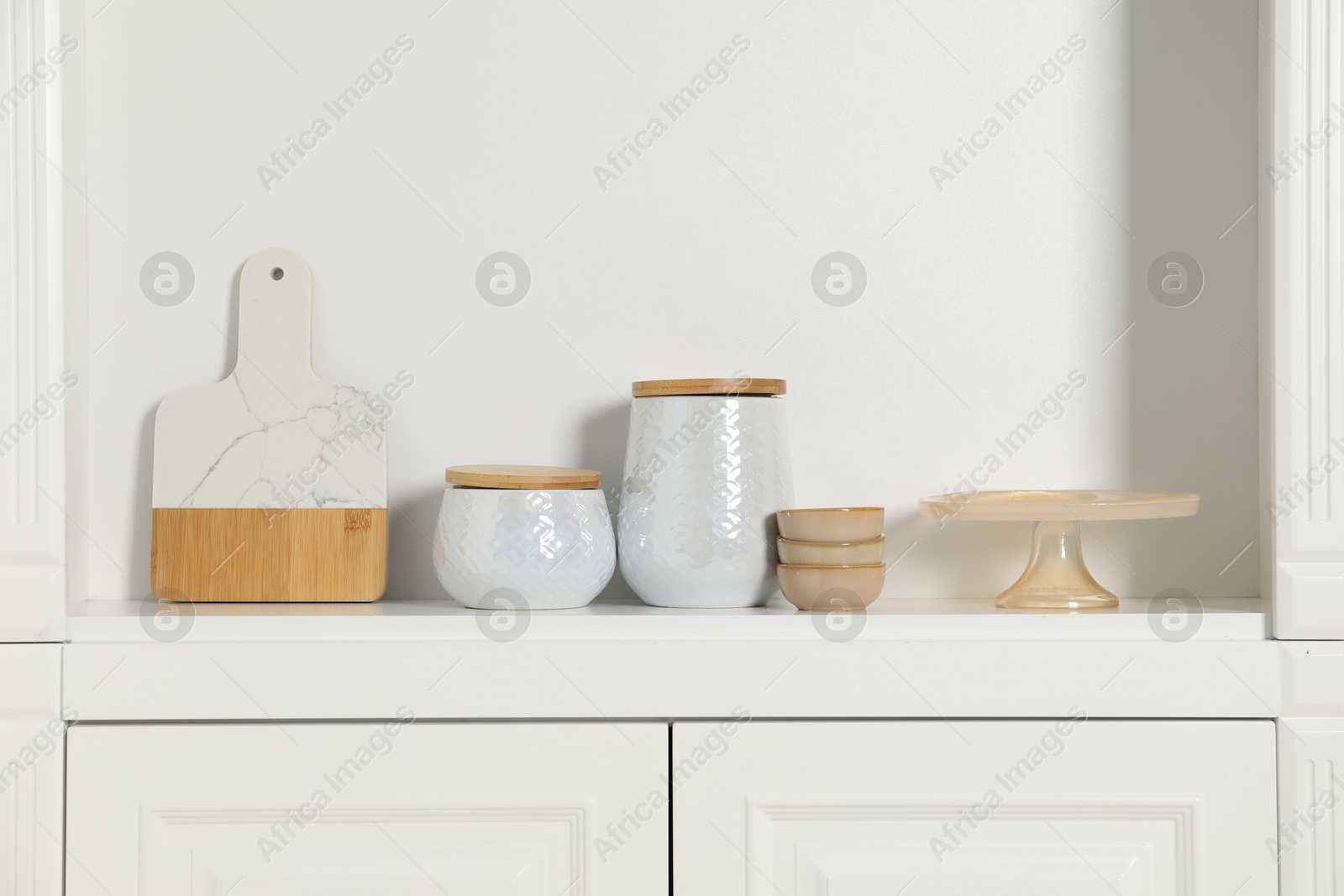 Photo of White shelving unit with different kitchenware indoors