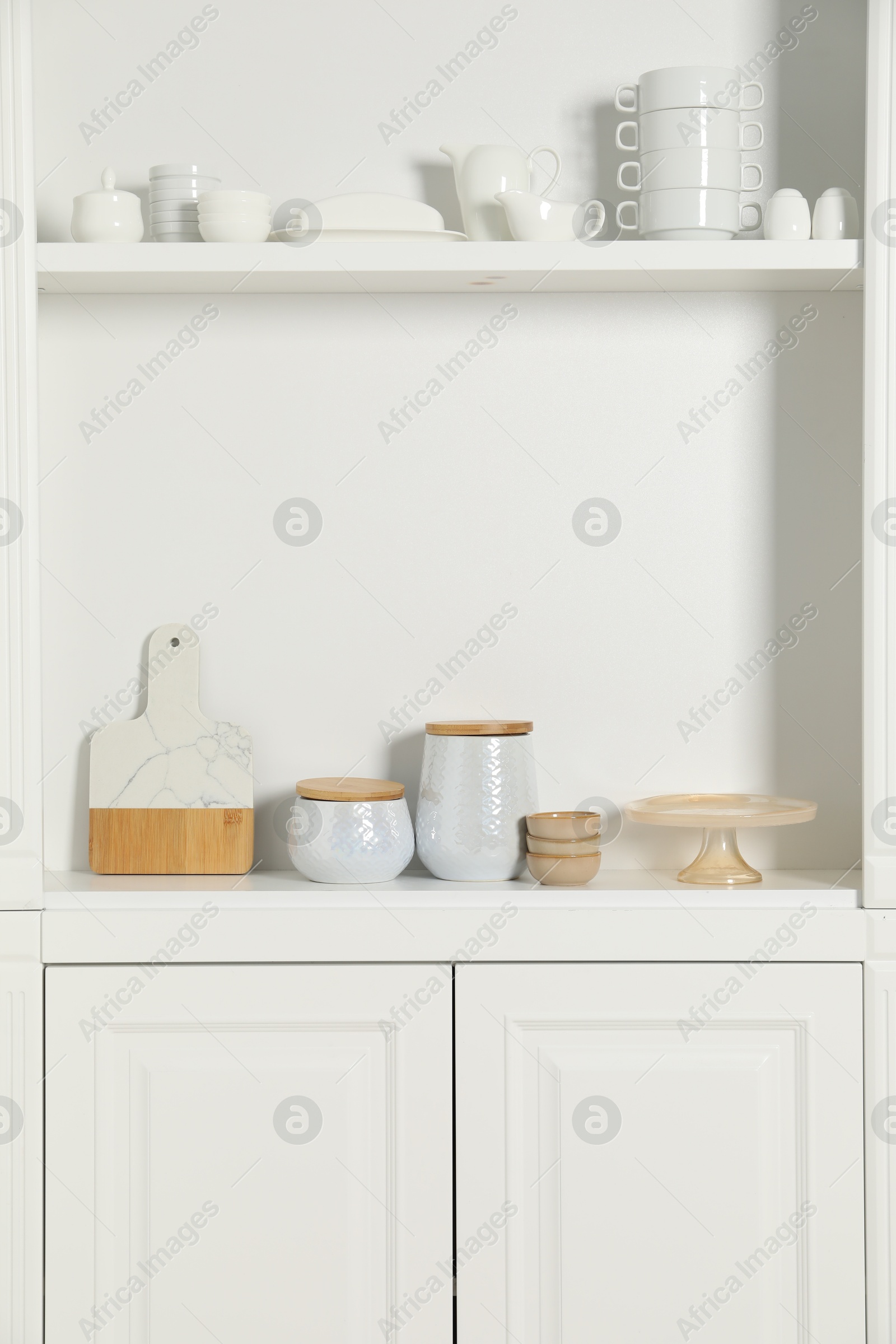 Photo of White shelving unit with different kitchenware indoors