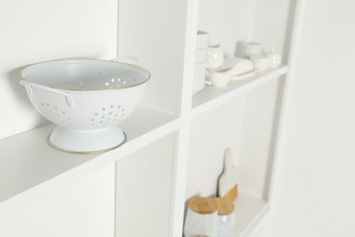 Photo of White shelving unit with kitchenware indoors, closeup