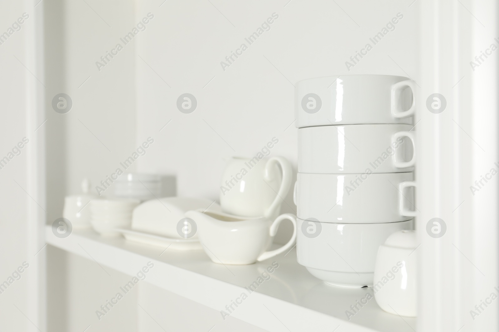 Photo of White shelving unit with dishware indoors, closeup