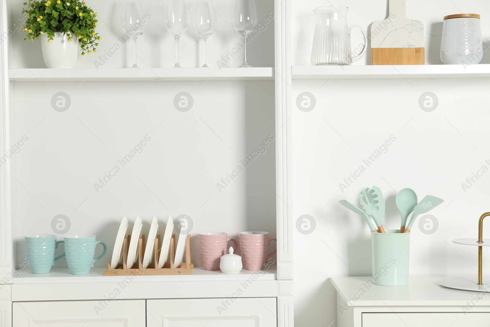 Photo of Shelving unit with different kitchenware near white wall indoors