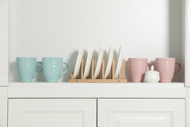 Photo of White shelving unit with different tableware indoors