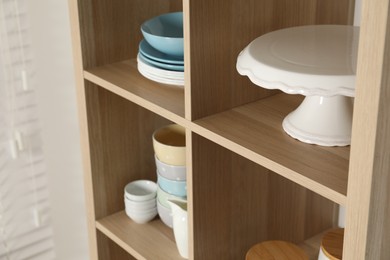 Photo of Wooden shelving unit with kitchenware indoors, closeup