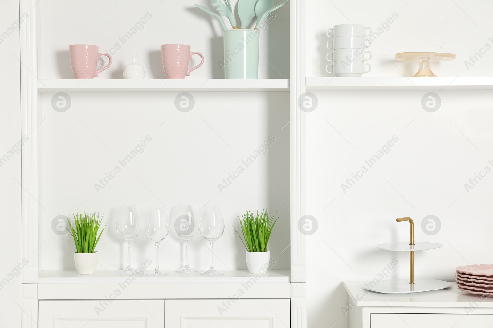 Photo of Shelving unit with different kitchenware near white wall indoors