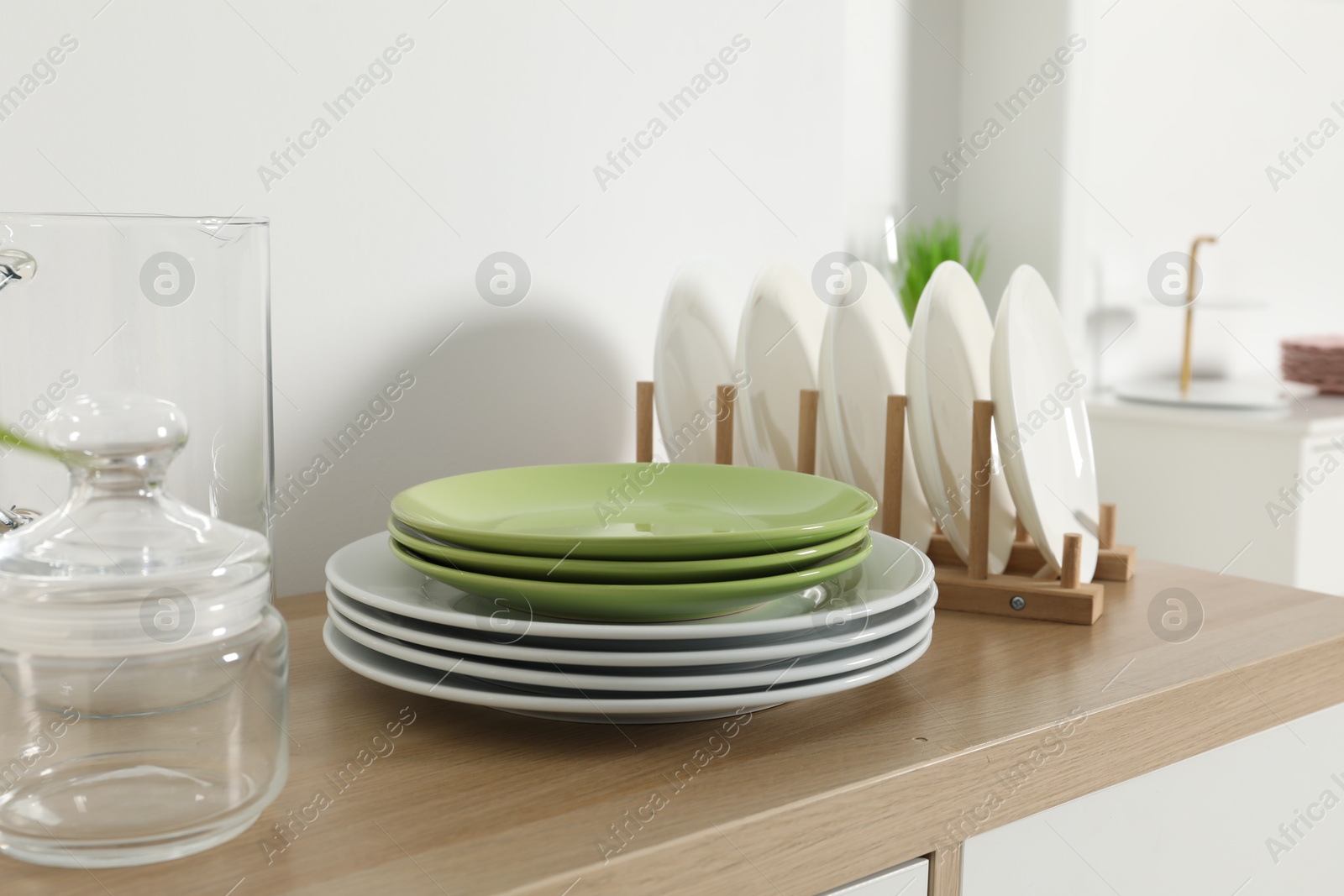 Photo of Tableware on wooden storage cabinet near white wall indoors