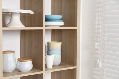 Wooden shelving unit with kitchenware near white wall indoors