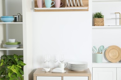 Shelving unit with different kitchenware near white wall indoors